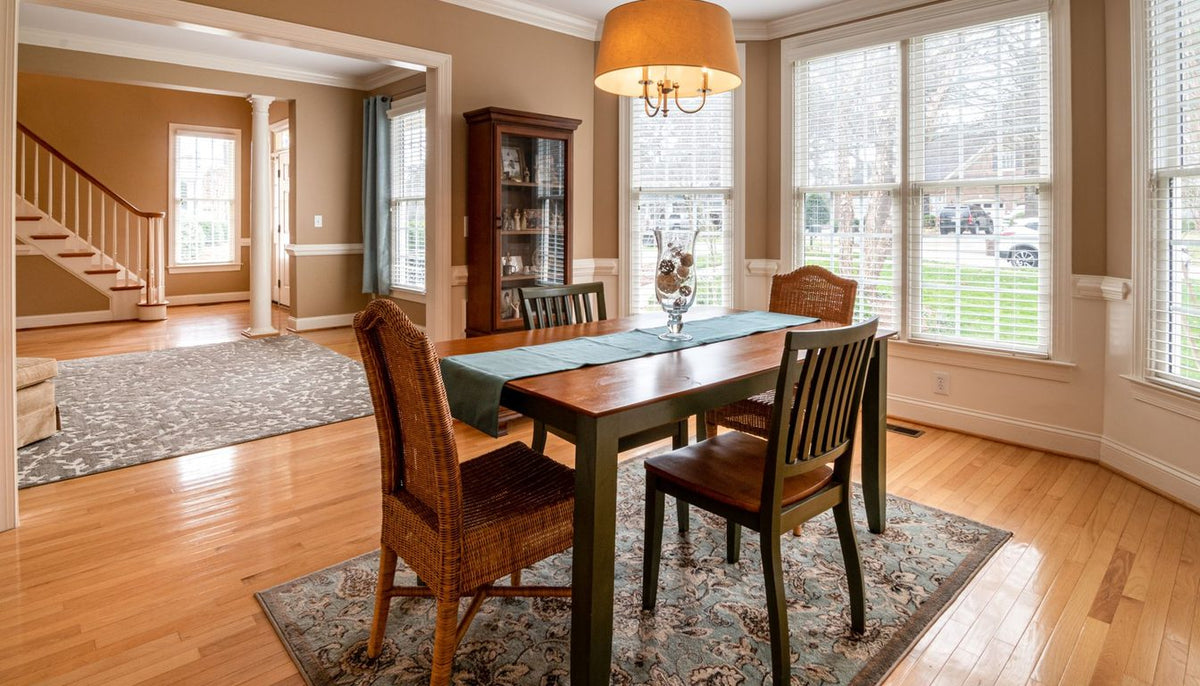 Salle à manger avec chaises habillées autour d'une table en bois, près d'une baie vitrée Image